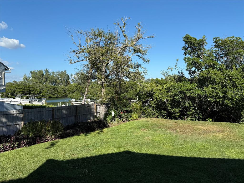 A grassy lawn extends toward a line of trees with a view of water beyond — 1515 PINELLAS BAYWAY S UNIT 42, ST PETERSBURG, FL