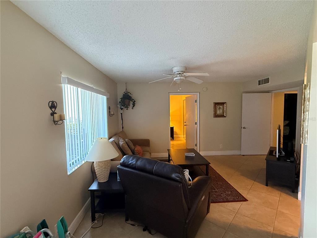 A kitchen with white cabinets, a breakfast bar with three stools, and tan walls — 1515 PINELLAS BAYWAY S UNIT 42, ST PETERSBURG, FL