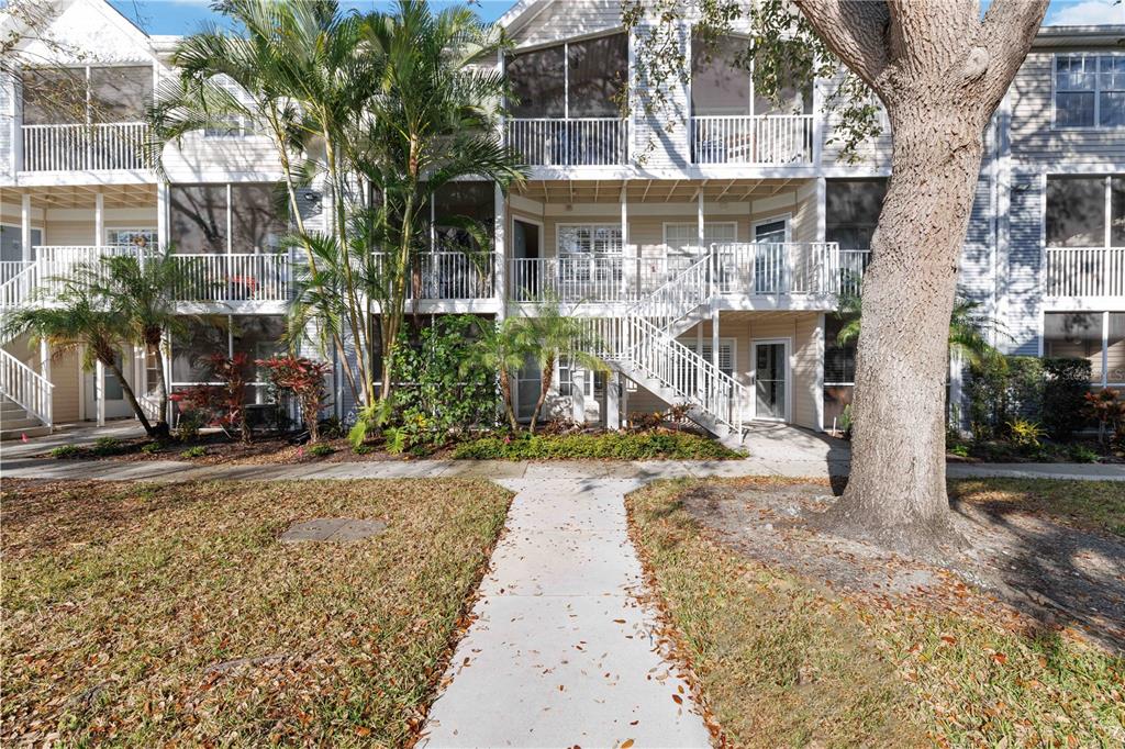 A multi-story apartment building features screened balconies, white railings, and an exterior staircase — 850 S TAMIAMI TRAIL UNIT 630, SARASOTA, FL