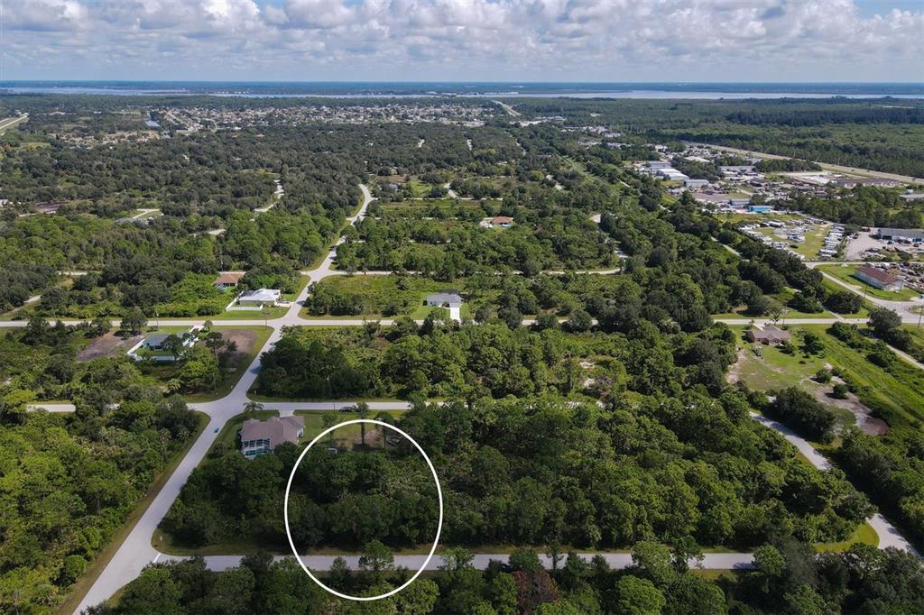 An aerial view shows a wooded, undeveloped residential lot circled in a suburban neighborhood — 13200 WAFFLE LANE, PORT CHARLOTTE, FL
