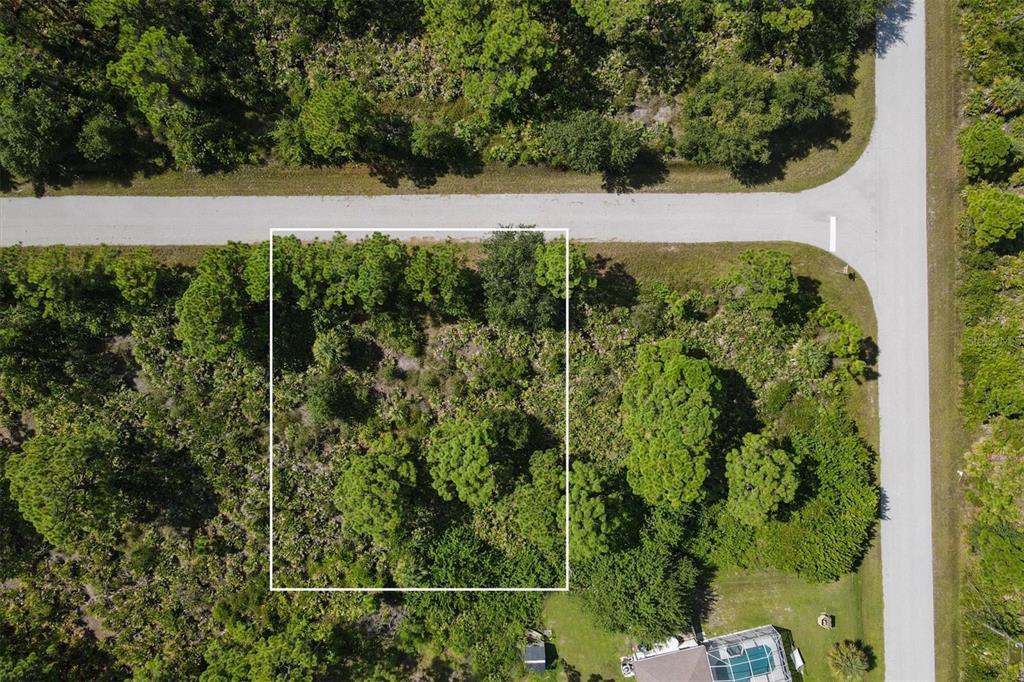 An aerial view shows a rectangular plot of land outlined in white near a road — 13200 WAFFLE LANE, PORT CHARLOTTE, FL