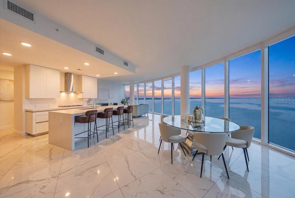 A modern kitchen and dining area feature marble floors, white cabinetry, and floor-to-ceiling windows — 2900 W BAY TO BAY BOULEVARD UNIT 1401, TAMPA, FL