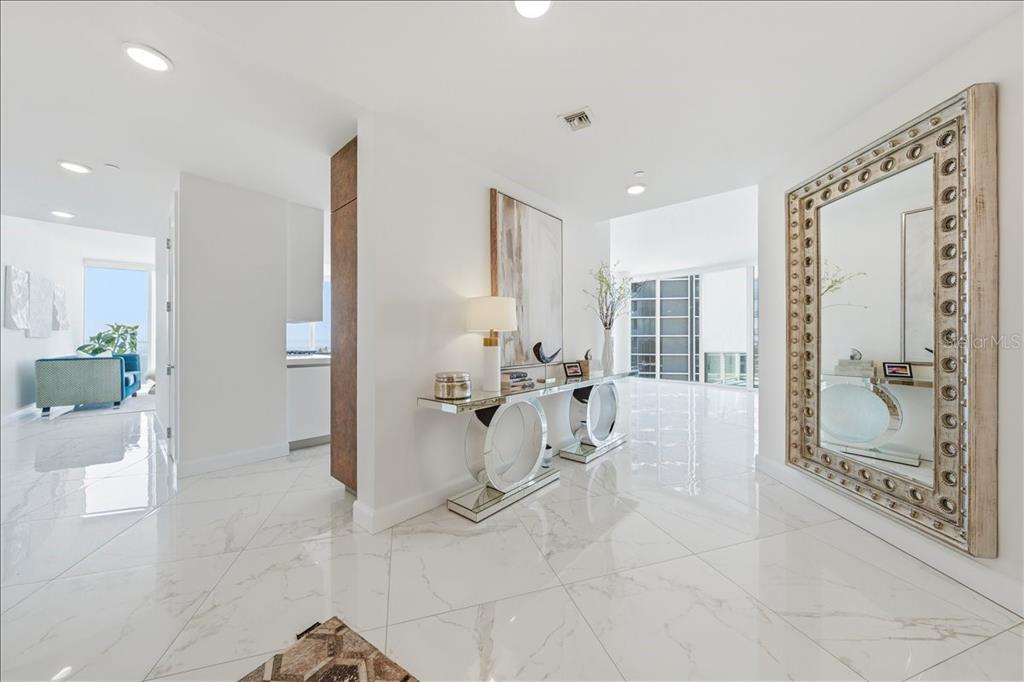 A bright foyer features white marble floors, a mirrored console table, and a large wall mirror — 2900 W BAY TO BAY BOULEVARD UNIT 1401, TAMPA, FL