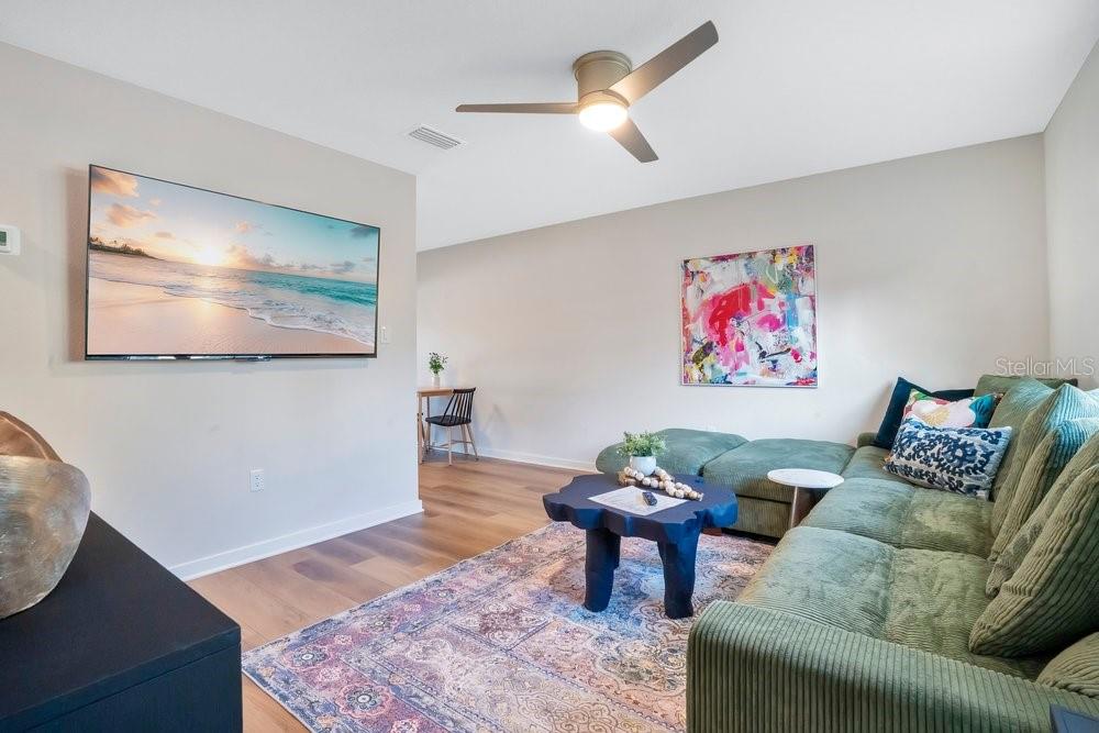 A living room features a green sectional sofa, a dark coffee table, and wall-mounted television — 122 E BELMAR STREET UNIT D, LAKELAND, FL