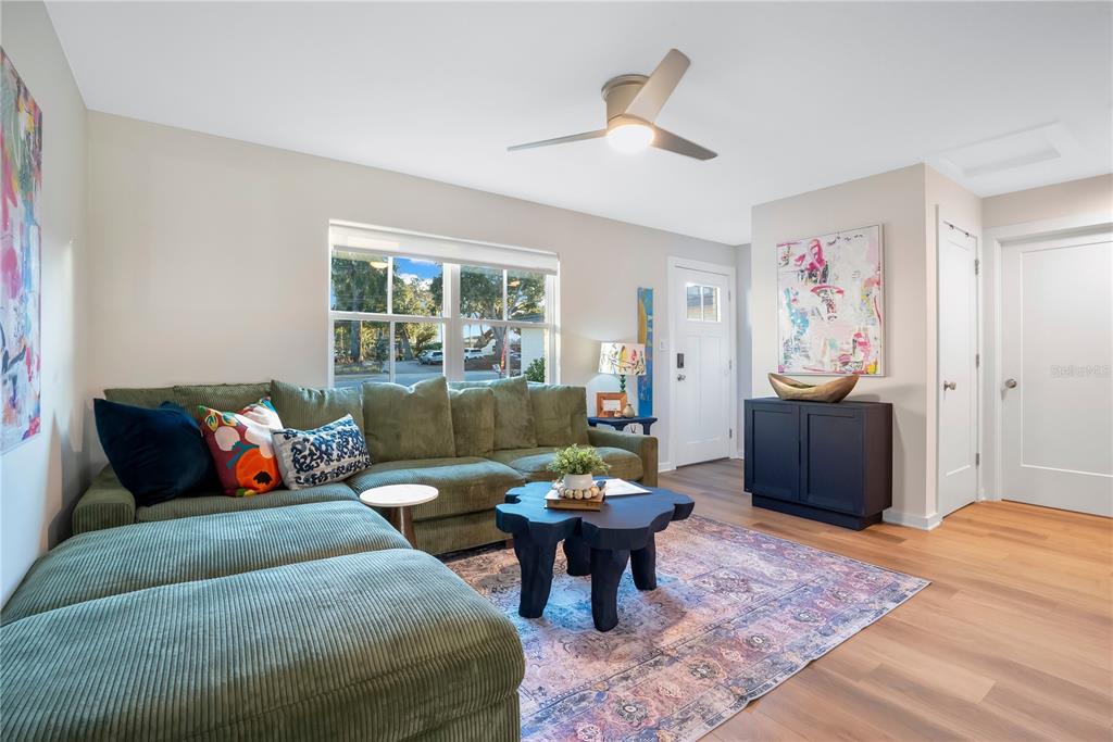 A living room features a green sectional sofa, a dark coffee table, and wood flooring — 122 E BELMAR STREET UNIT D, LAKELAND, FL