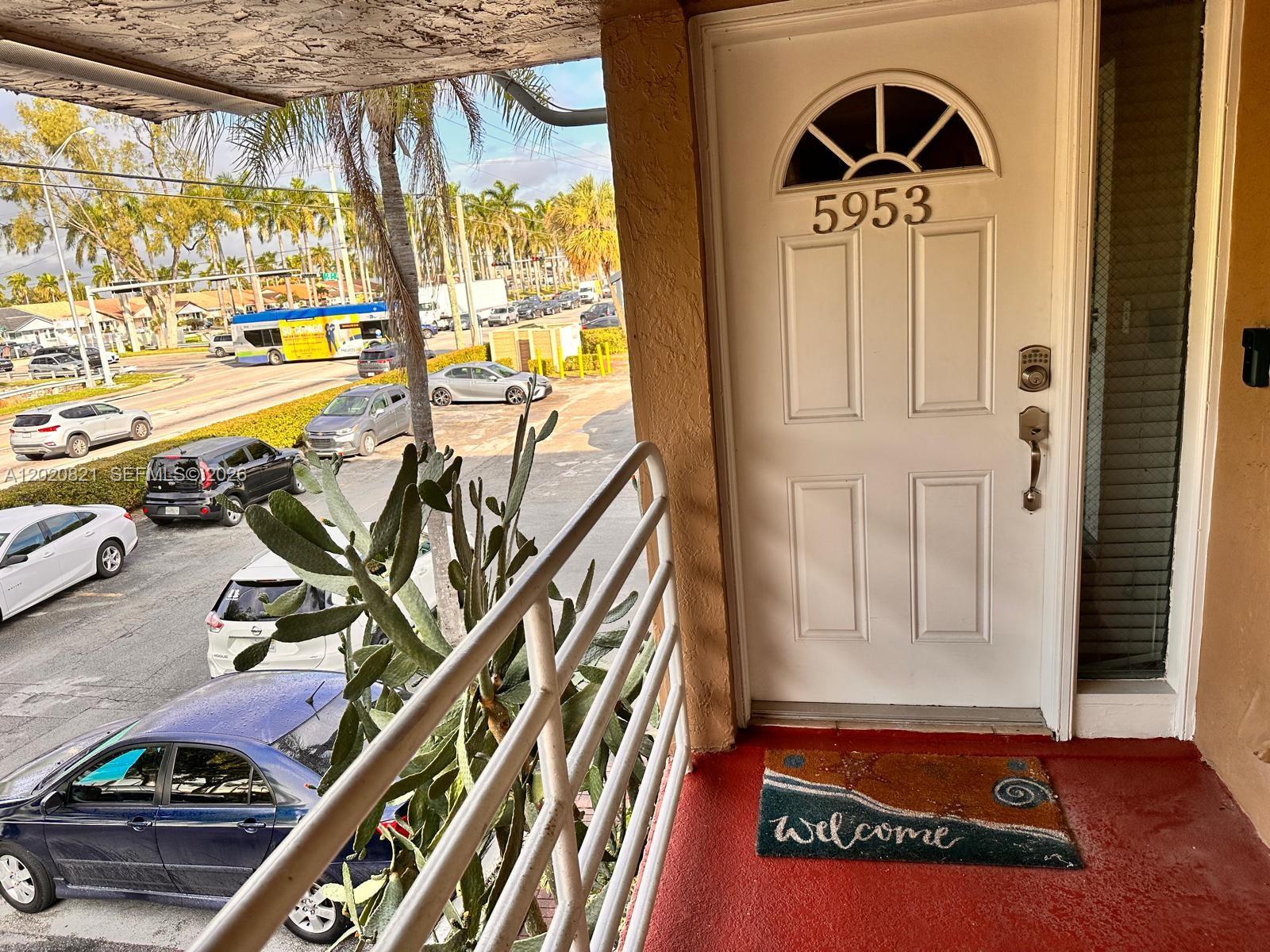 A white front door with a transom window opens onto a balcony overlooking a parking lot — 5953 W 28th Ave # 24, Hialeah FL 33016, HIALEAH, FL