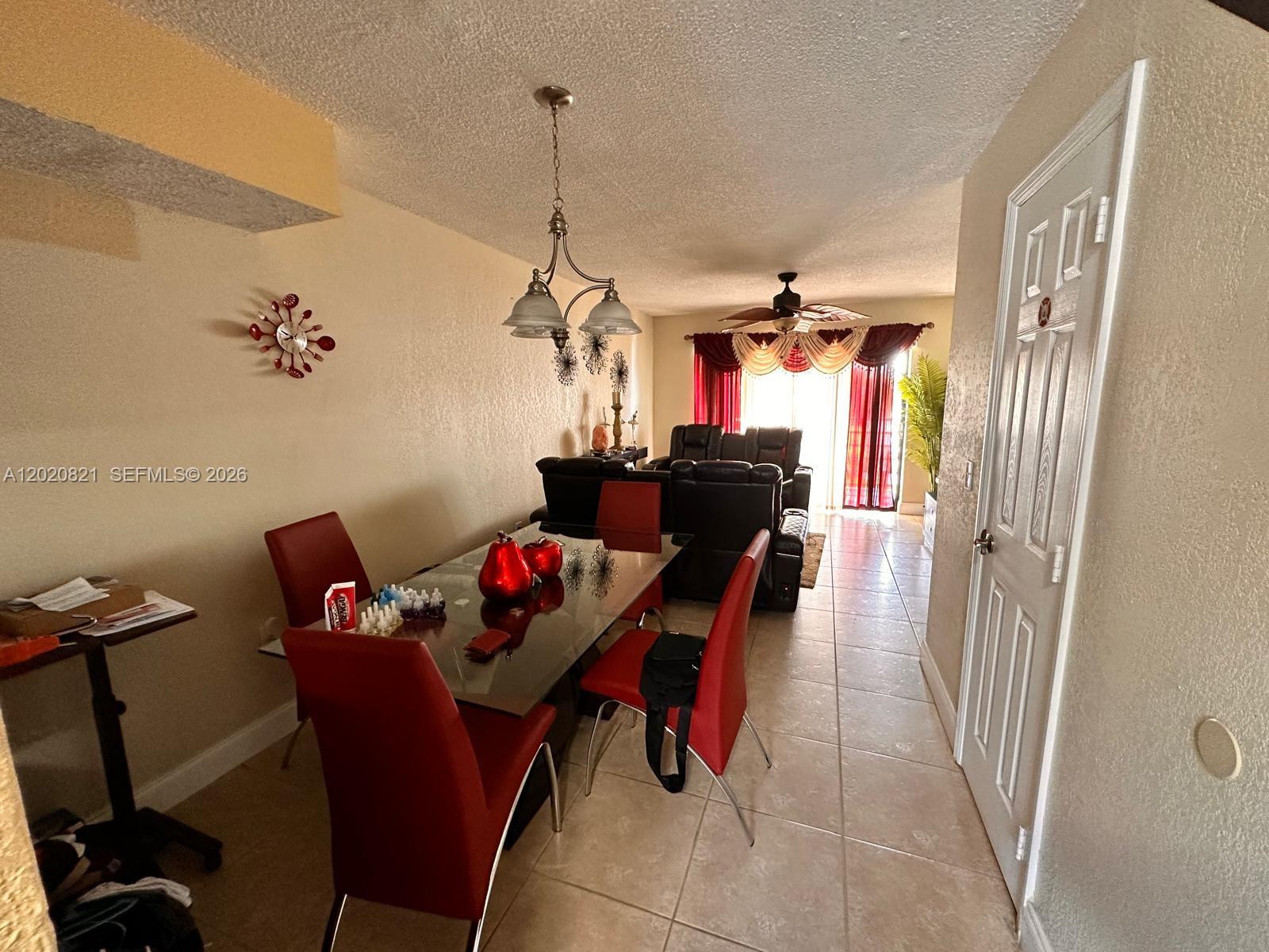 A dining area with a glass table and red chairs leads into a living room — 5953 W 28th Ave # 24, Hialeah FL 33016, HIALEAH, FL