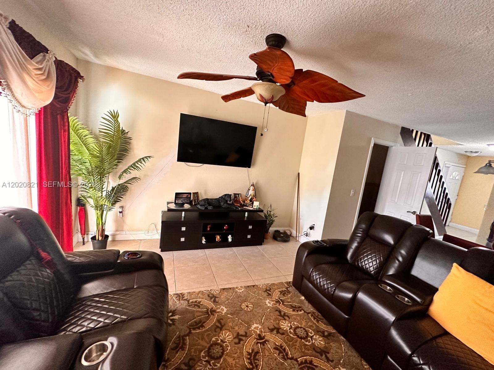 A living room features dark leather recliners, a television, and a leaf-shaped ceiling fan — 5953 W 28th Ave # 24, Hialeah FL 33016, HIALEAH, FL