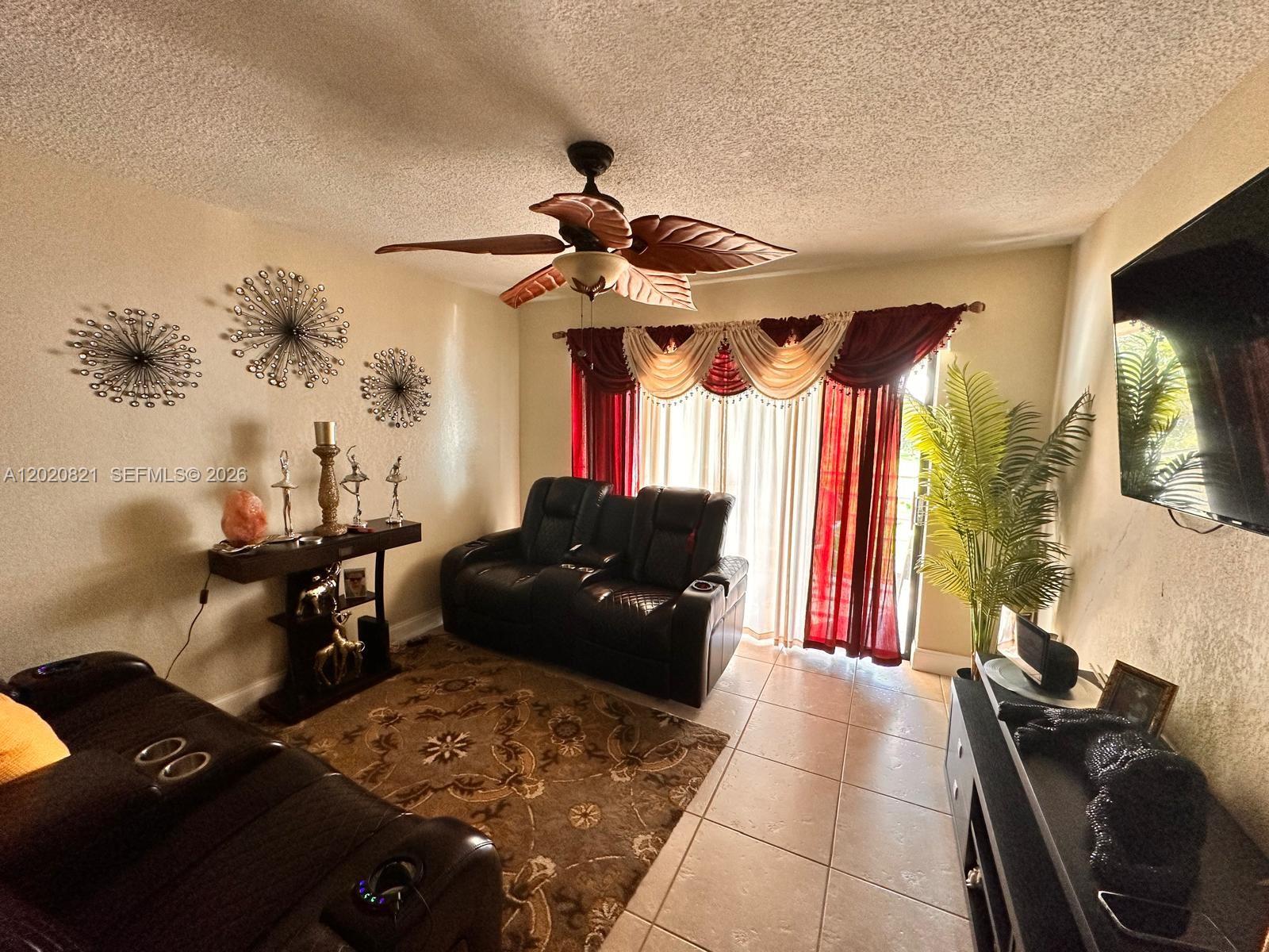 A living room features a ceiling fan, leather recliners, a patterned rug, and red curtains — 5953 W 28th Ave # 24, Hialeah FL 33016, HIALEAH, FL