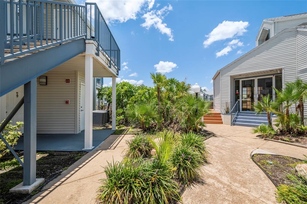 An outdoor walkway leads between a multi-story building with stairs and a single-story building — 2568 WOODGATE BOULEVARD UNIT 107, ORLANDO, FL