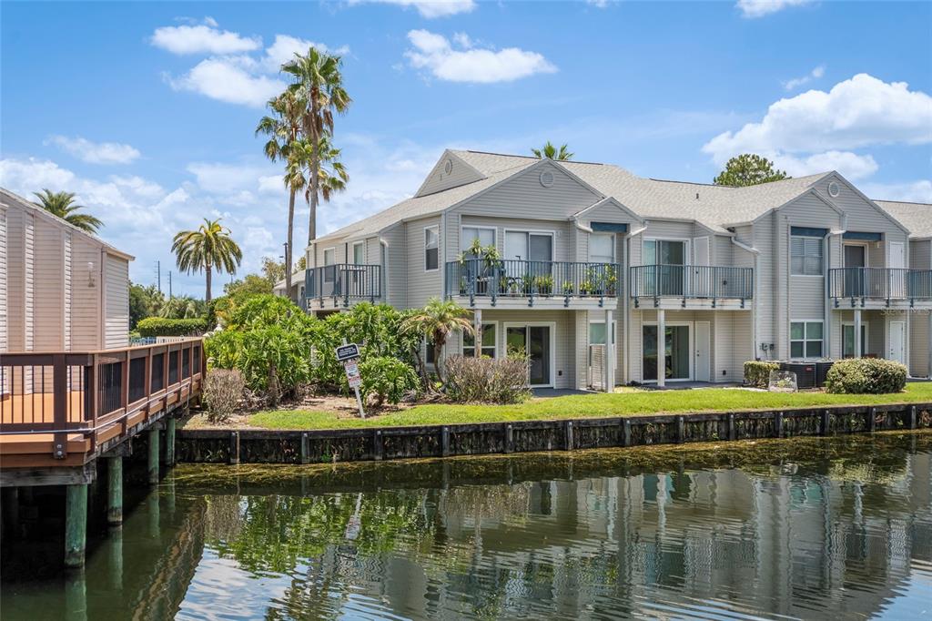 A two-story apartment building with balconies sits beside a canal on a sunny day — 2568 WOODGATE BOULEVARD UNIT 107, ORLANDO, FL
