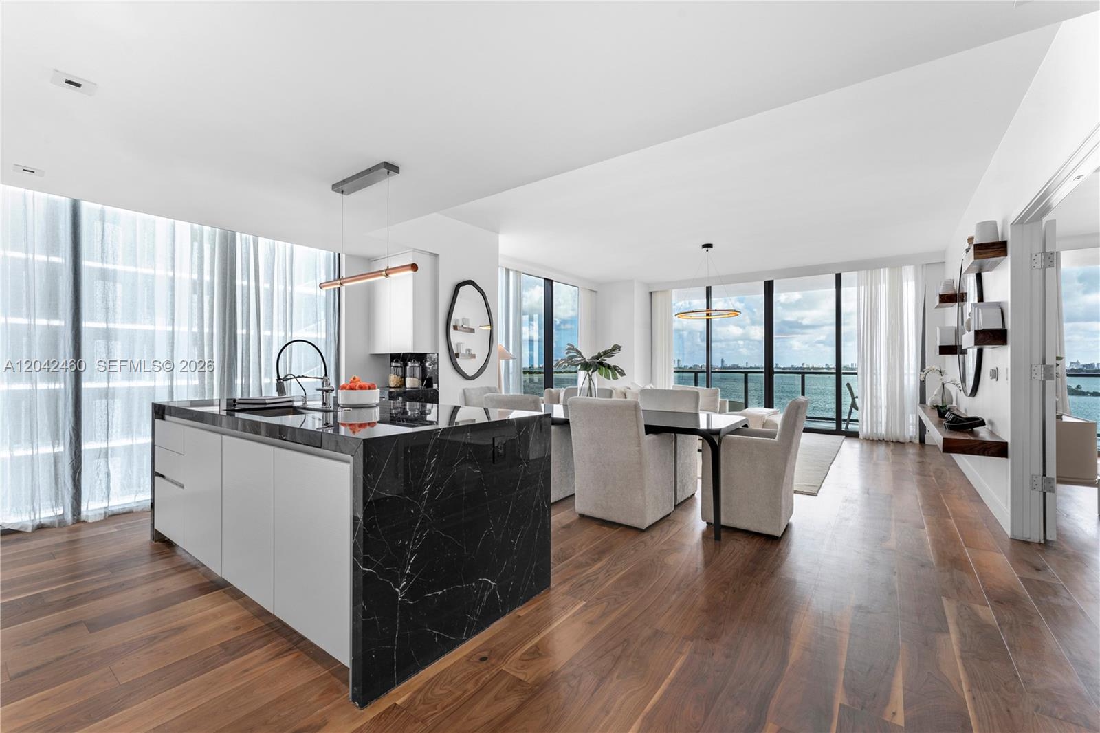 A modern kitchen and dining area feature a black marble island and floor-to-ceiling windows — 788 NE 23rd St # 902, Miami FL 33137, MIAMI, FL