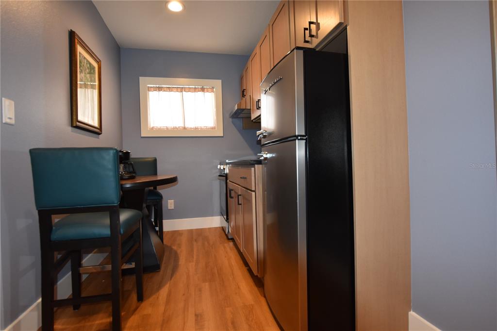 A small kitchen features light wood cabinets, stainless steel appliances, and a dining area — 704 S LAKESHORE BOULEVARD, HOWEY IN THE HILLS, FL