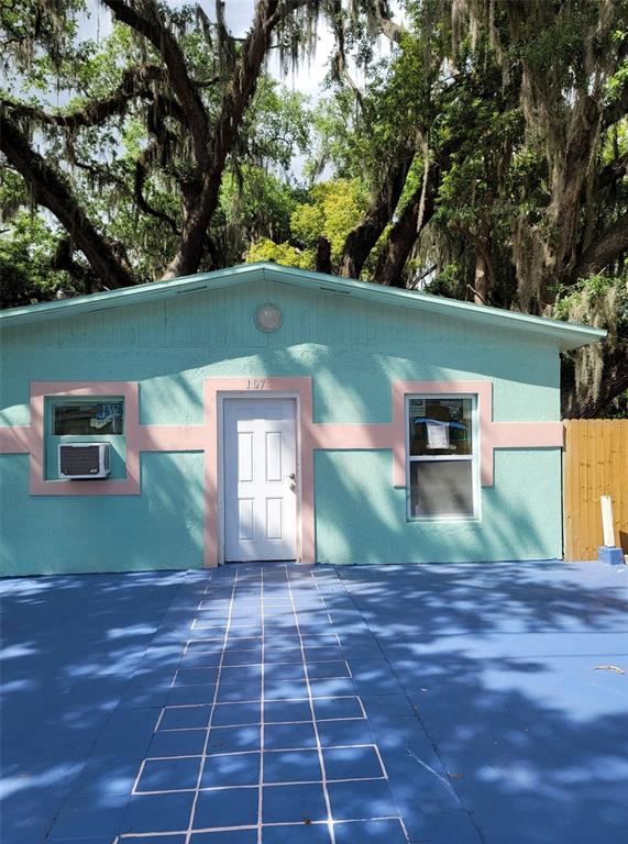 A light blue house with pink trim and a painted hopscotch grid on the ground — 107 E CYPRESS STREET, KISSIMMEE, FL
