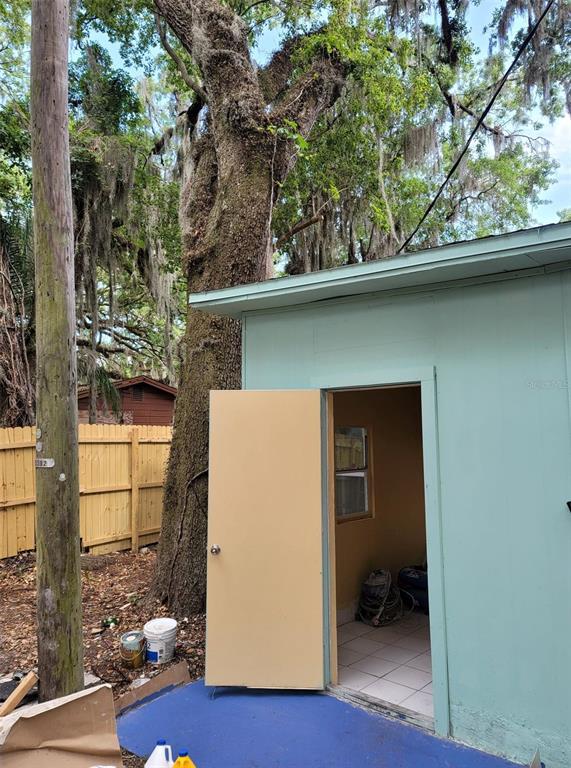 A light green shed with an open door stands next to a large oak tree — 107 E CYPRESS STREET, KISSIMMEE, FL