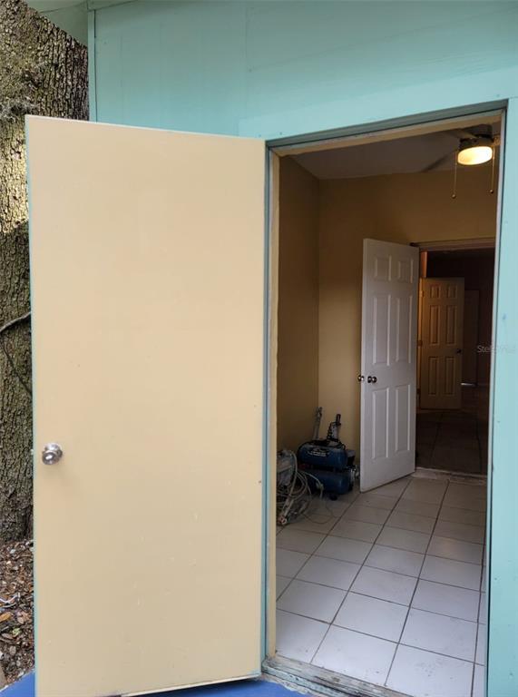 An open exterior door reveals a small tiled utility room with a second interior door — 107 E CYPRESS STREET, KISSIMMEE, FL