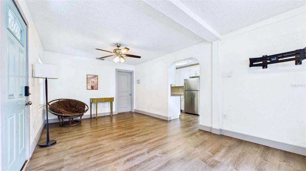 A living room with wood-look flooring, a ceiling fan, and an arched doorway to the kitchen — 5457 72ND AVENUE N, PINELLAS PARK, FL