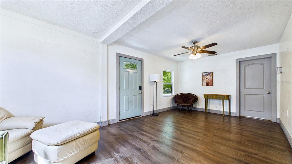 A living room features white walls, wood-look flooring, a ceiling fan, and a front door — 5457 72ND AVENUE N, PINELLAS PARK, FL