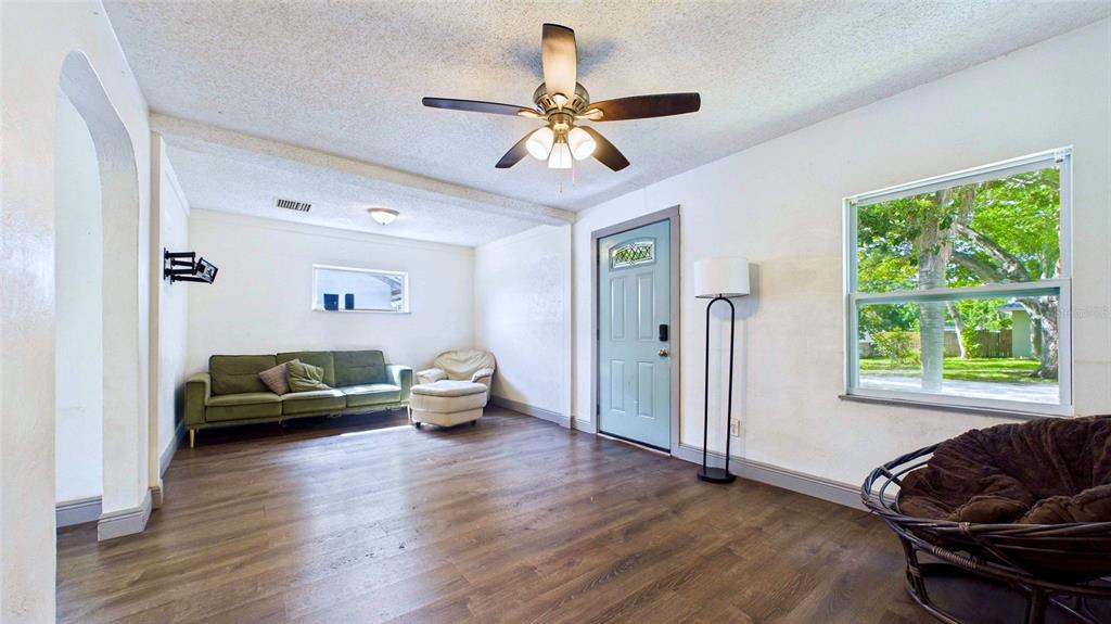 A living room features wood-look flooring, a ceiling fan, a green sofa, and a window — 5457 72ND AVENUE N, PINELLAS PARK, FL