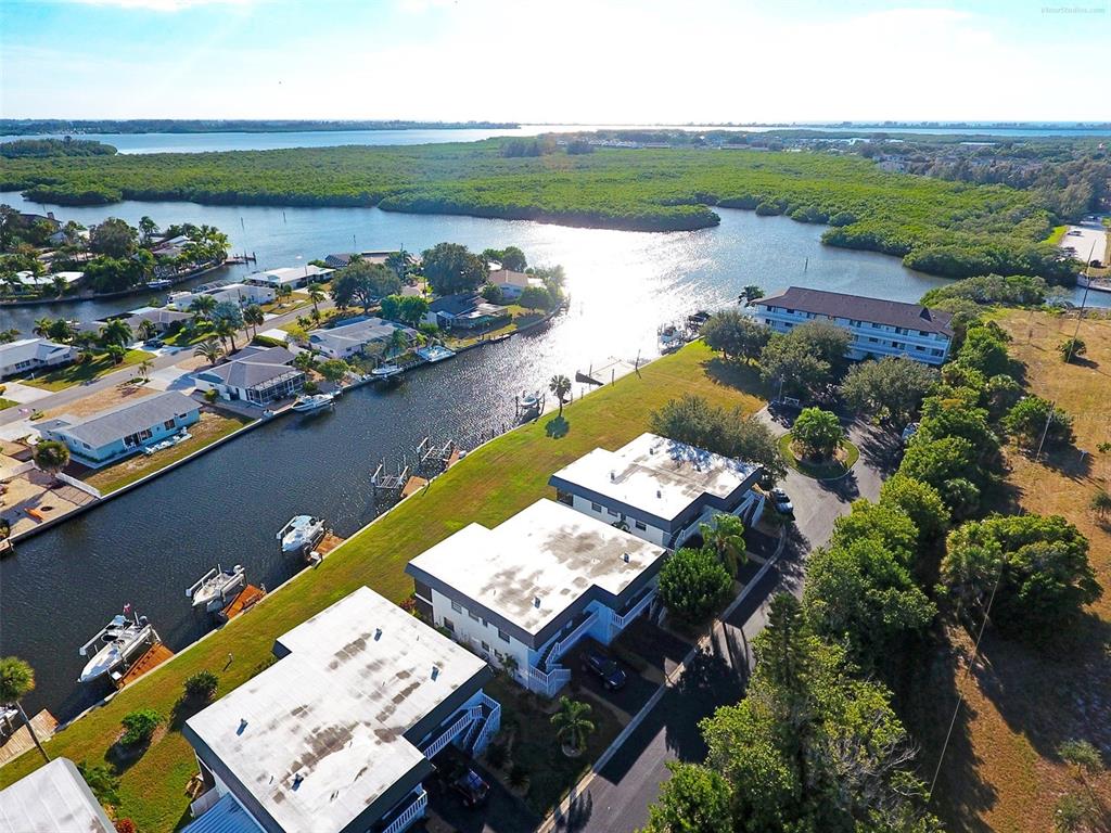 An aerial view shows waterfront townhomes with boat docks along a canal near mangroves — 10431 WATERBIRD WAY UNIT 10431, BRADENTON, FL