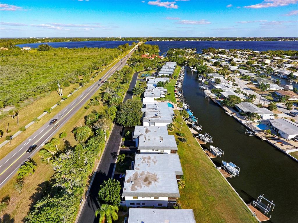 An aerial view shows a row of waterfront townhomes beside a canal and a highway — 10431 WATERBIRD WAY UNIT 10431, BRADENTON, FL