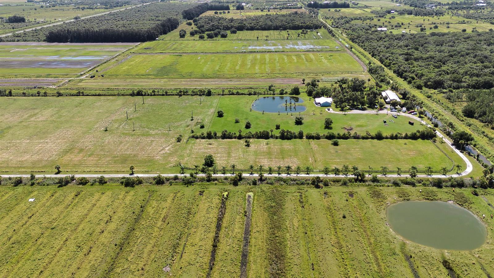 An aerial view shows a rural property with green fields, two ponds, and several buildings — 18601 Orange Avenue, Fort Pierce FL 34945, FORT PIERCE, FL