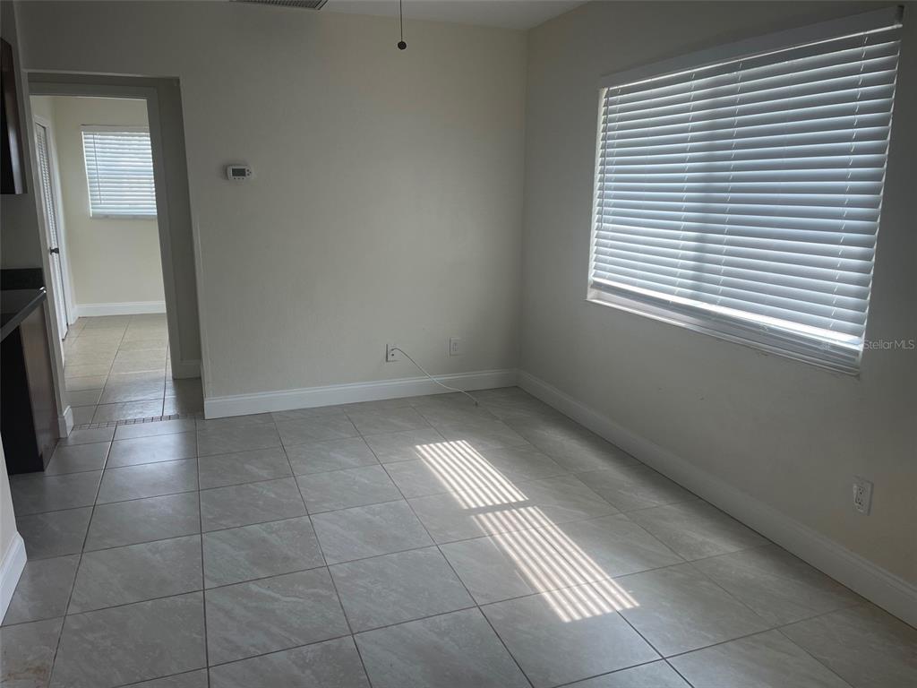 A room with light-colored tile flooring, white walls, and a window with horizontal blinds — 5066 3RD STREET N, ST PETERSBURG, FL