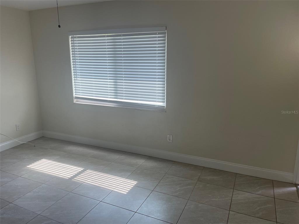 An empty room features light-colored tile flooring, white walls, and a window with horizontal blinds — 5066 3RD STREET N, ST PETERSBURG, FL