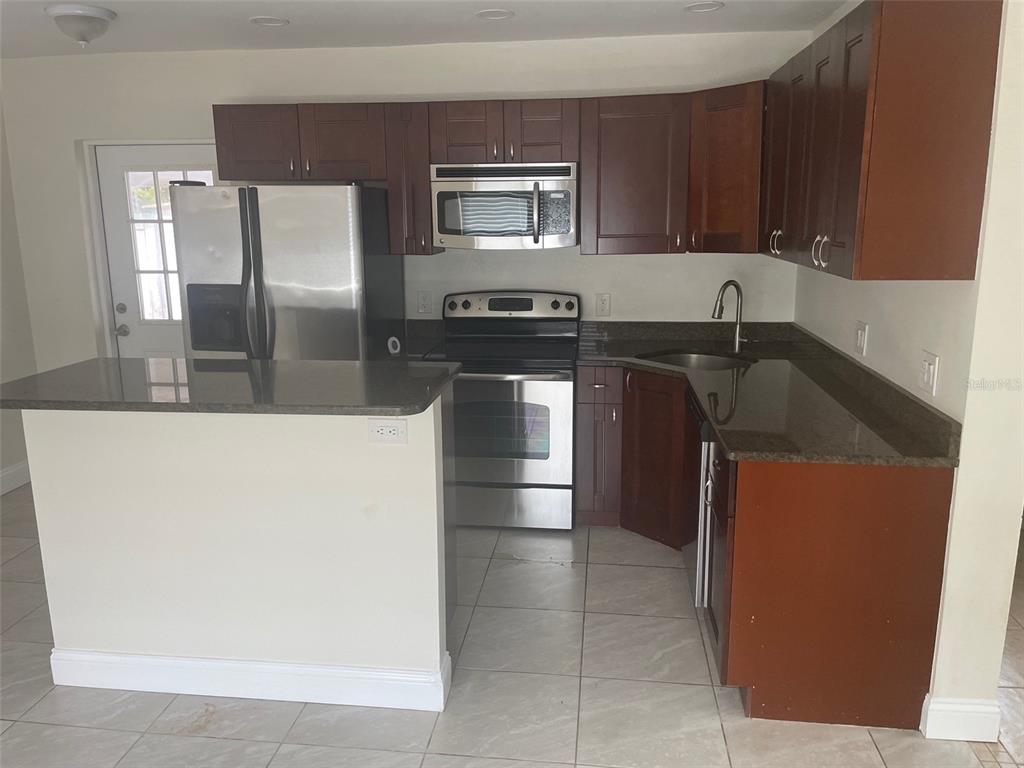 A kitchen features dark wood cabinets, granite countertops, stainless steel appliances, and light tile flooring — 5066 3RD STREET N, ST PETERSBURG, FL