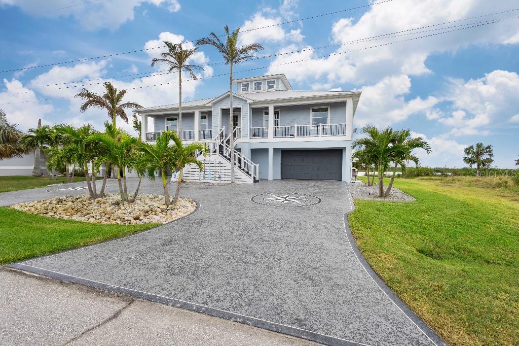 A two-story coastal house with a gray garage, elevated porch, and a decorative paved driveway — 16176 LA BARGE CIRCLE, PORT CHARLOTTE, FL
