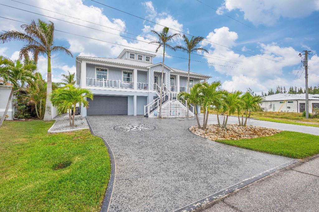 A two-story house with a gray exterior, elevated porch, and a decorative concrete driveway — 16176 LA BARGE CIRCLE, PORT CHARLOTTE, FL