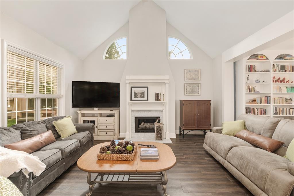 A living room features a vaulted ceiling, a fireplace, two sofas, and built-in bookshelves — 5512 NW 51ST AVENUE, GAINESVILLE, FL