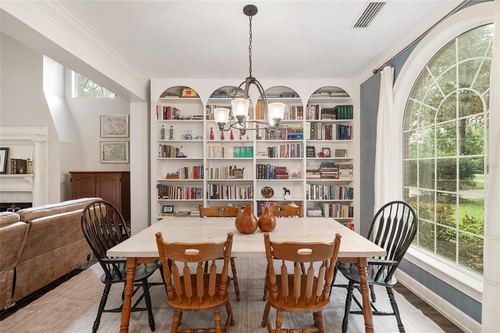 A dining room features a light wood table, wooden chairs, and built-in white bookshelves — 5512 NW 51ST AVENUE, GAINESVILLE, FL