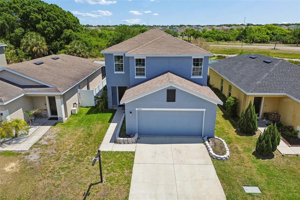 An aerial view shows a two-story blue house with a garage and a concrete driveway — 11926 GRAND KEMPSTON DRIVE, GIBSONTON, FL