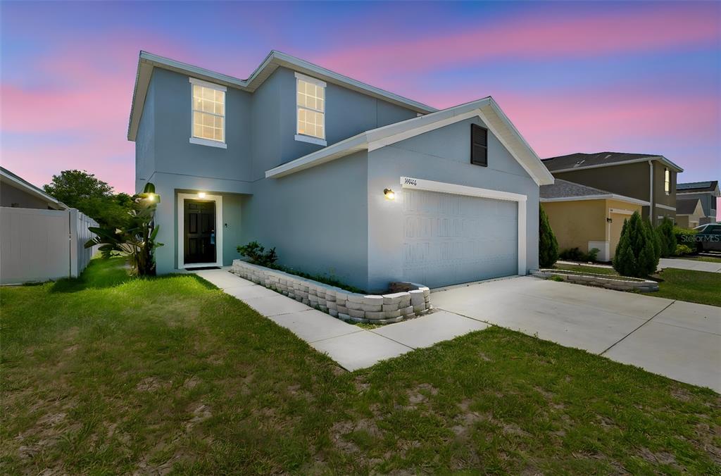 A two-story blue house with a two-car garage and a small stone retaining wall — 11926 GRAND KEMPSTON DRIVE, GIBSONTON, FL