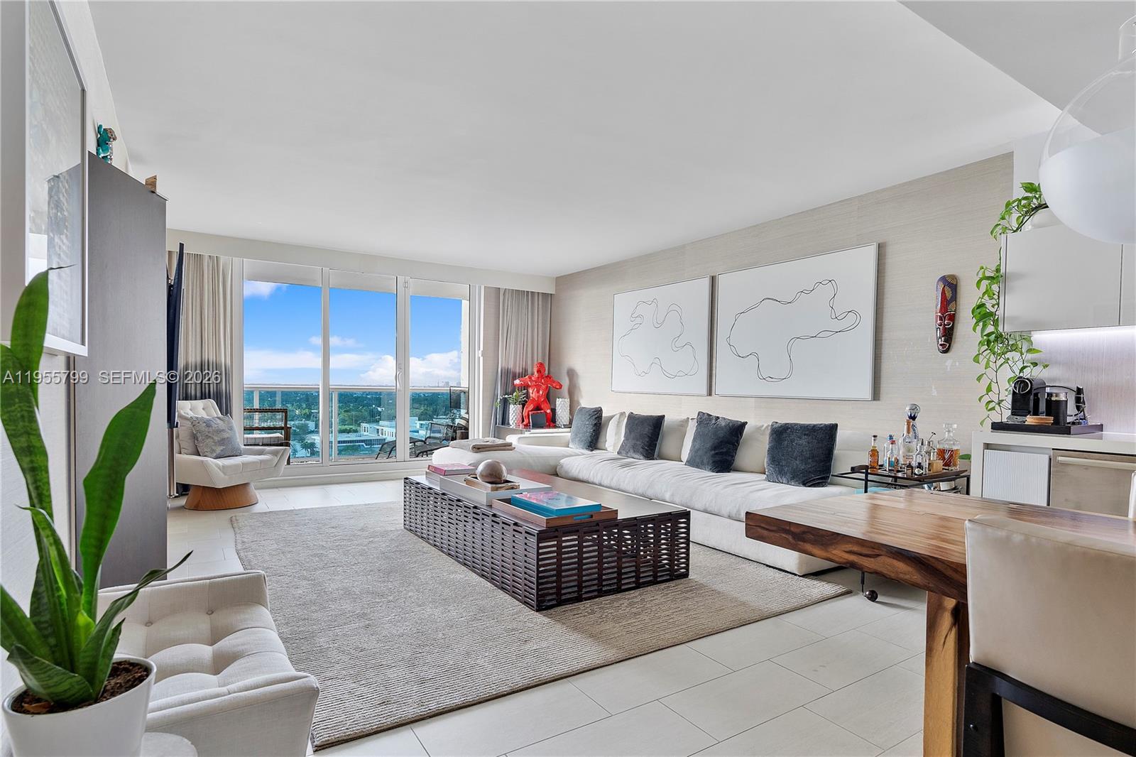 A modern living room features a large sectional sofa, a coffee table, and balcony views — 102 24th St # 1427, Miami Beach FL 33139, MIAMI BEACH, FL