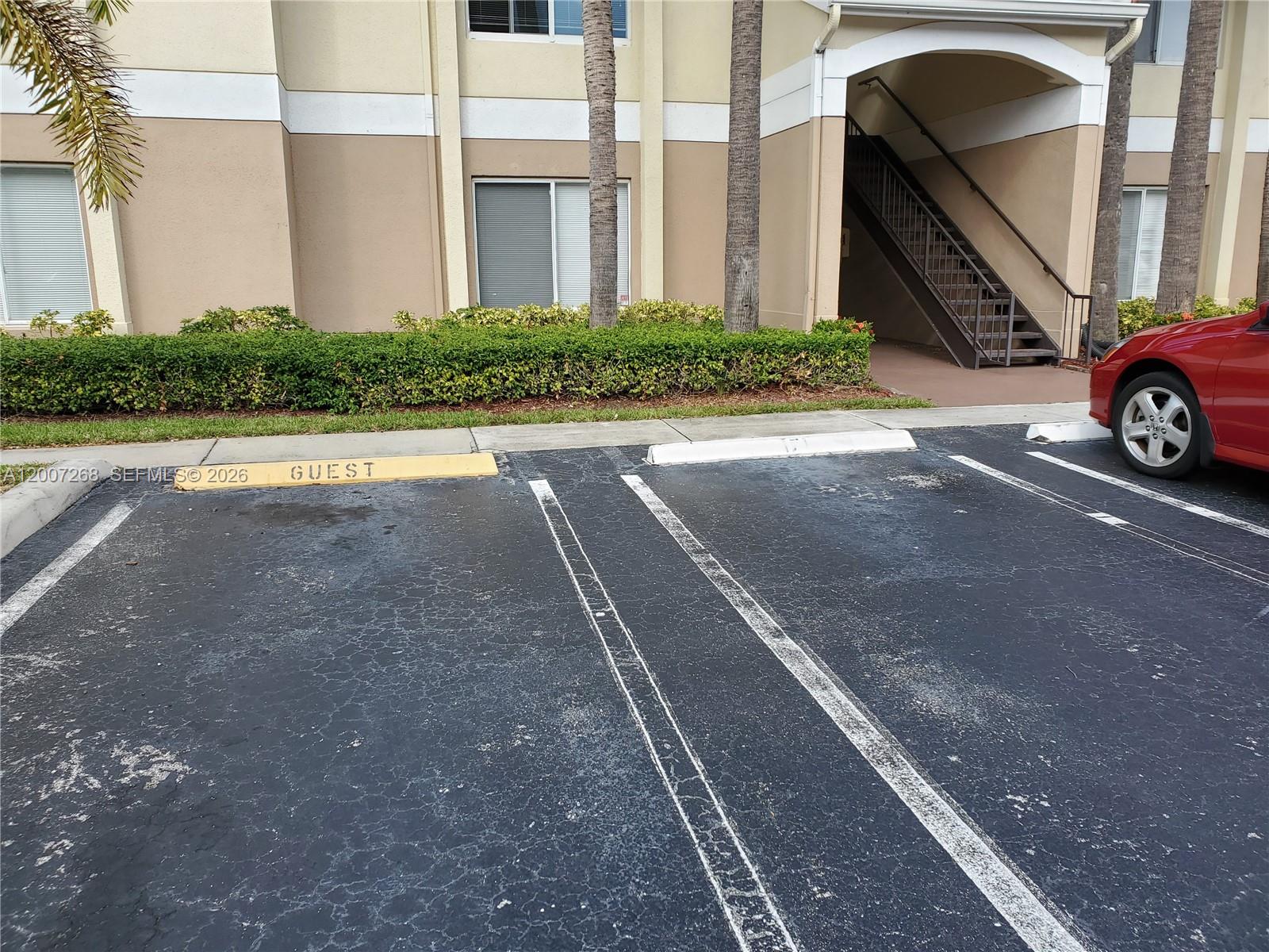 A red car is parked in a guest parking space in front of an apartment building — 815 W Boynton Beach Blvd # 102, Boynton Beach FL 33426, BOYNTON BEACH, FL
