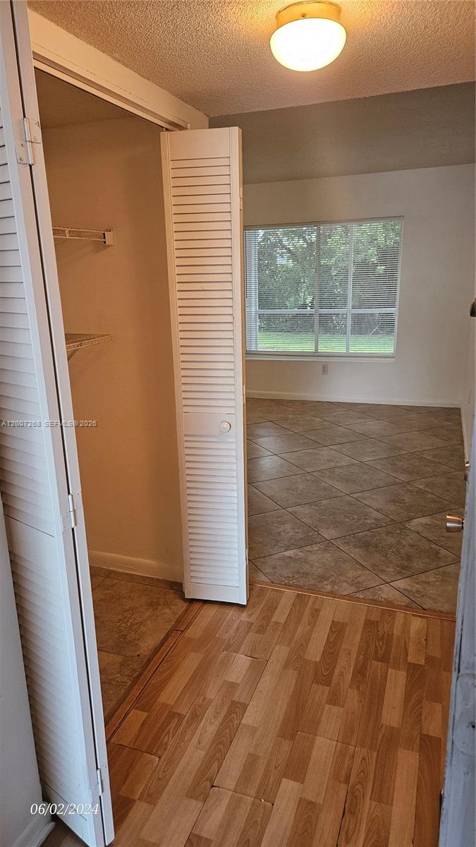 A room with tiled floors and a large window is viewed through an open closet — 815 W Boynton Beach Blvd # 102, Boynton Beach FL 33426, BOYNTON BEACH, FL