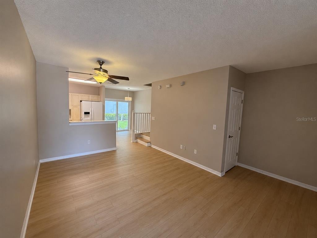 An open-concept living room with light wood-look flooring, beige walls, and a ceiling fan — 6030 OSPREY LAKE CIRCLE, RIVERVIEW, FL