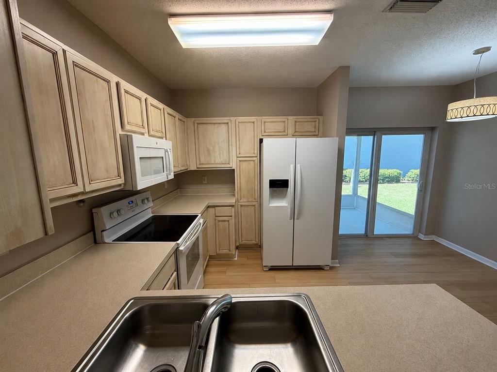 A kitchen features light-colored wood cabinets, a white refrigerator, and a stainless steel sink — 6030 OSPREY LAKE CIRCLE, RIVERVIEW, FL