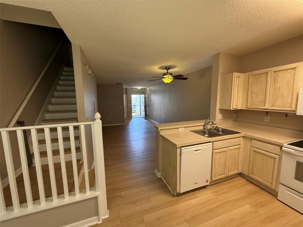 A kitchen with light wood cabinets and a dishwasher overlooks a living area with stairs — 6030 OSPREY LAKE CIRCLE, RIVERVIEW, FL