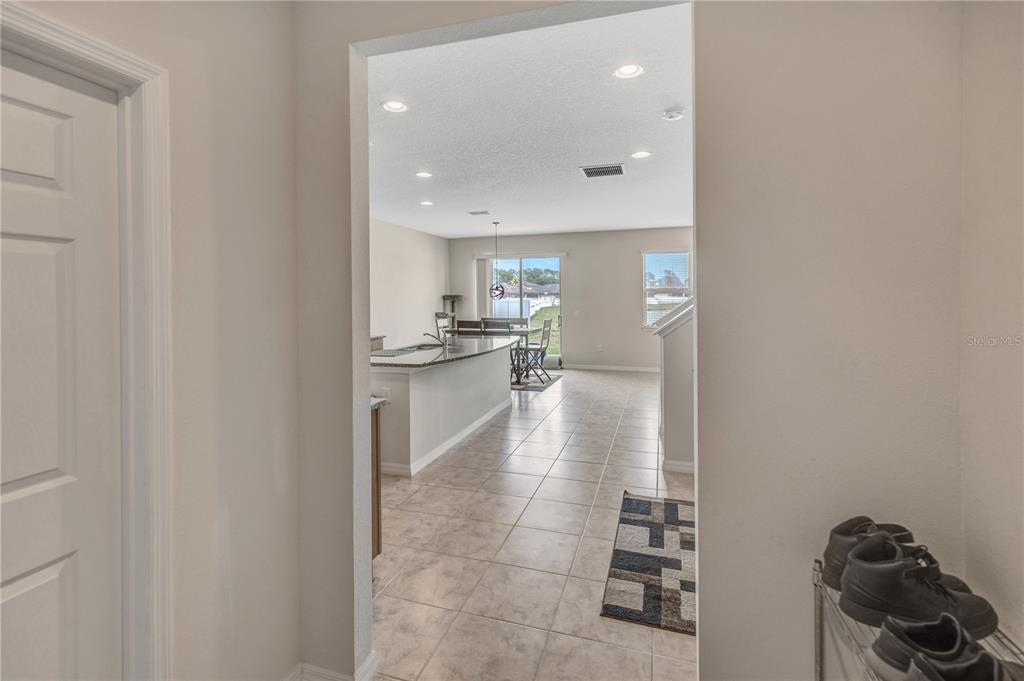 A view from a doorway looking into an open-concept kitchen and dining area with tile — 8811 ASHLAND AVENUE, POLK CITY, FL