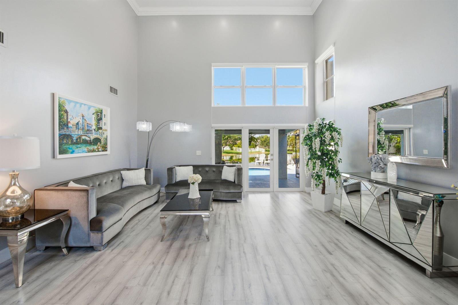 A spacious living room features gray velvet sofas, a mirrored console, and high ceilings — 14040 Richwood Place, Davie FL 33325, DAVIE, FL