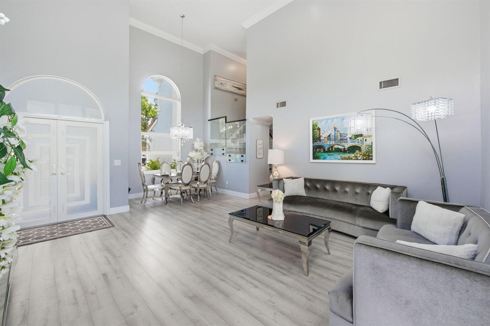 A living and dining area with high ceilings, gray velvet furniture, and light wood flooring — 14040 Richwood Place, Davie FL 33325, DAVIE, FL