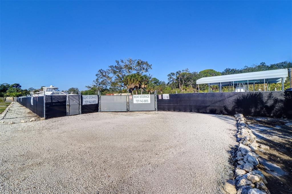 A gravel lot features a fenced boat storage area with a covered boat slip — 332 ANCLOTE ROAD, TARPON SPRINGS, FL