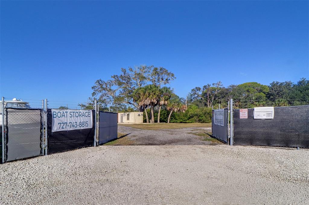 An outdoor boat storage lot is enclosed by a chain-link fence with a gravel entrance — 332 ANCLOTE ROAD, TARPON SPRINGS, FL