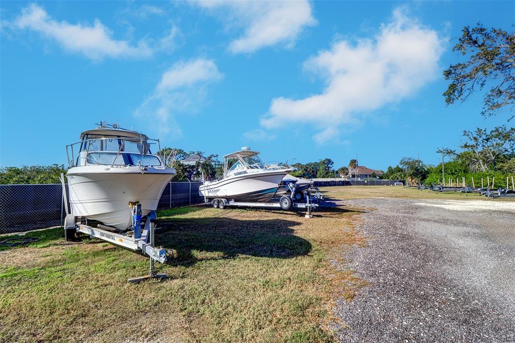 Two boats on trailers are parked in a grassy lot next to a gravel driveway — 332 ANCLOTE ROAD, TARPON SPRINGS, FL