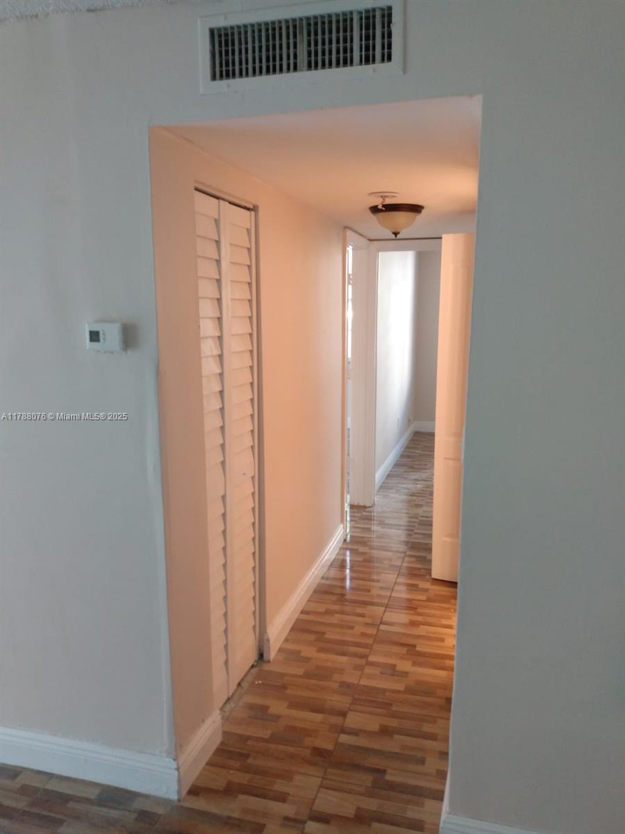 A hallway features wood-look tile flooring, a louvered closet door, and a ceiling light fixture — 494 NW 165th St Rd # 102, Miami FL 33169, MIAMI, FL