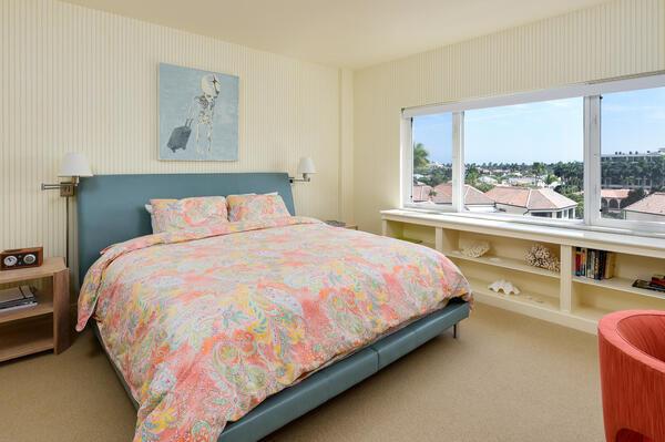 A bedroom features a blue bed frame, a patterned comforter, and a large window view — 250 Bradley Place # 609, Palm Beach FL 33480, PALM BEACH, FL