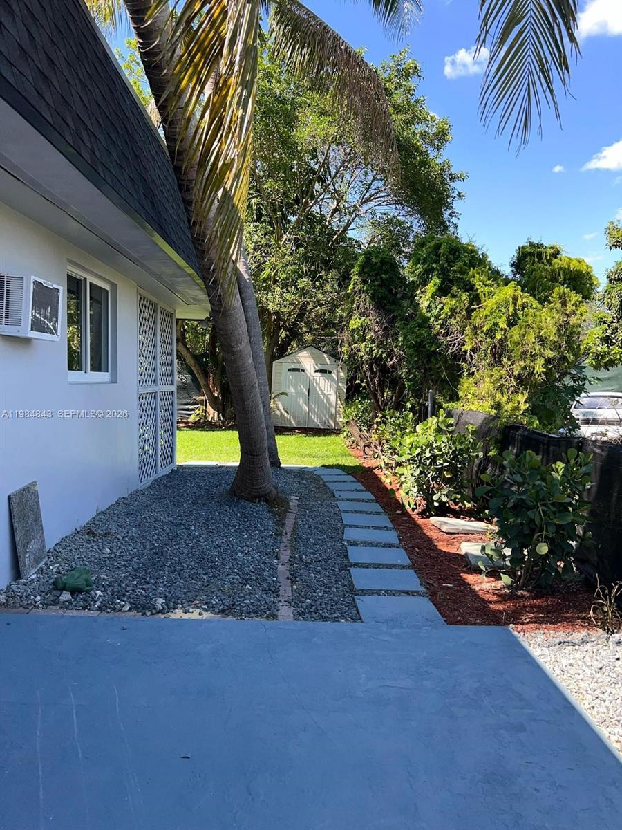 A backyard features a concrete patio, a gravel area, a stone path, and a storage shed — 161 NE 117th St, Miami FL 33161, MIAMI, FL